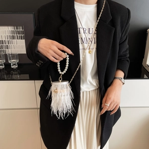 Detailed view of white ostrich feather mini bucket bag with pearl handle and gold chain