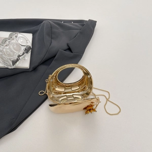 Detail of gold metal crescent evening clutch with acrylic flower and ring handle