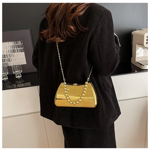 Detail of gold metallic clutch bag featuring a beaded handle and elegant chain strap