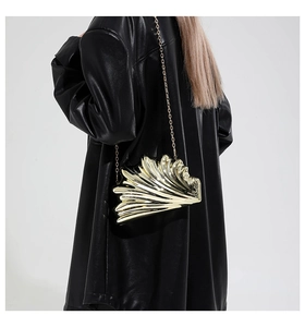 Close-up of golden shell-shaped metal clutch with wavy texture and fine chain strap