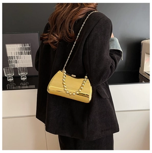 Detail of gold metallic evening clutch bag with chain strap and beaded handle on model