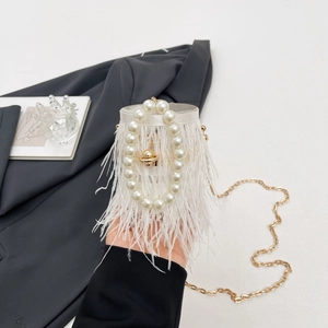 Detail of white ostrich feather bucket bag featuring a large pearl handle and gold chain