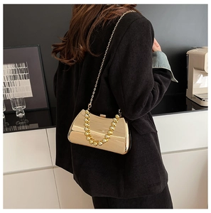 Close-up of gold mirror evening bag featuring a beaded handle and metal chain strap