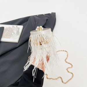 Detailed close-up of white feather clutch with pearl clasp and golden chain strap