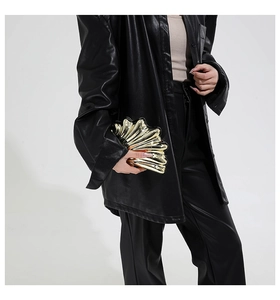 Fashionable gold shell shaped metal clutch bag held by model in black outfit