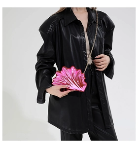Detail of metallic rose pink shell-shaped crossbody bag with a golden chain strap