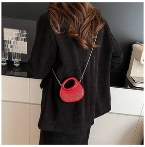 Detailed view of red acrylic evening bag with vertical ribbing and gold chain strap
