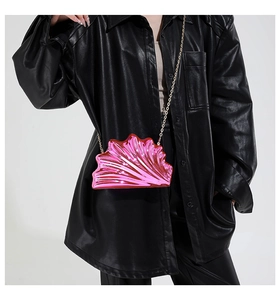 Metallic shell-shaped crossbody bag in vibrant purple with golden chain strap on model
