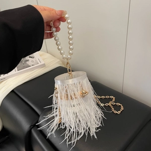 Close-up of white ostrich feather bucket bag with pearl handle and gold chain