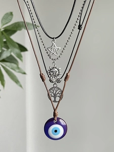 Close-up of bohemian layered necklaces with star, sun, and purple evil eye charms