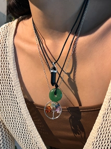 Close-up of layered necklace set with crystal pendant and tree of life on knitwear