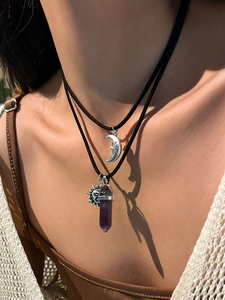 Close-up of bohemian layered necklace with silver moon and purple crystal pendant