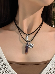 Detail of layered bohemian necklace with silver sun, moon charms and purple crystal prism