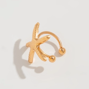 Detail of a gold starfish ear cuff featuring textured metallic finish and polished beads