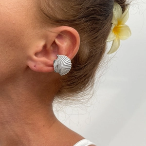Close-up of silver sea shell ear cuff with vertical texture worn on a model's ear