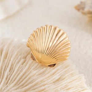 Detailed view of a gold starfish ear cuff placed on white coral for a coastal aesthetic