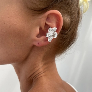 Close-up of a silver textured flower ear cuff worn by a model for a chic holiday look