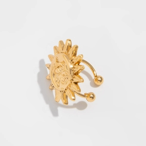 Detailed view of a gold sun face ear cuff with radiant rays on a white background