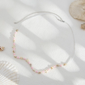 Détail de perles coquillage et étoile de mer sur une chaîne de taille style plage et bohème
