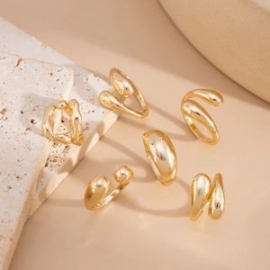 Detailed view of six-piece gold liquid metal ring set on textured stone base
