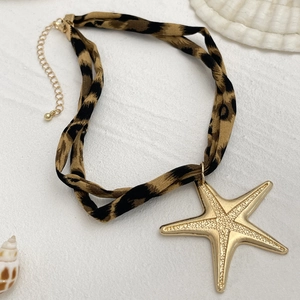 Detail der Leopardenmuster-Stoff-Choker mit großem goldenen Seestern-Anhänger und Muscheln