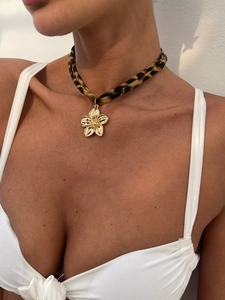 Nahaufnahme eines Leopard-Chokers mit goldenem Blumenanhänger am Hals des Models