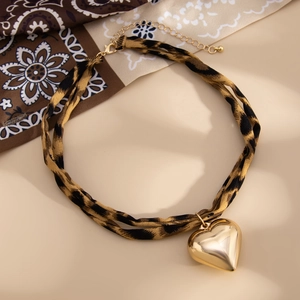 Detail eines Choker-Halsbandes mit Leopardenmuster und glänzendem goldener Herzanhänger