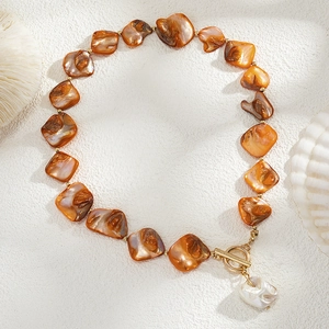 Detail of amber beaded necklace with gold toggle clasp and baroque pearl pendant