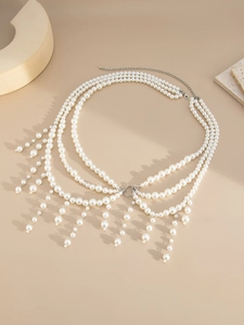 Macro detail of layered faux pearl body chain with silver tassels and adjustable clasp