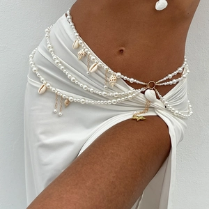 Detail view of multilayer pearl body chain with seashell charms on white dress