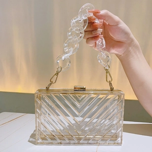Detailed close-up of a clear acrylic clutch bag featuring geometric V-shaped textures