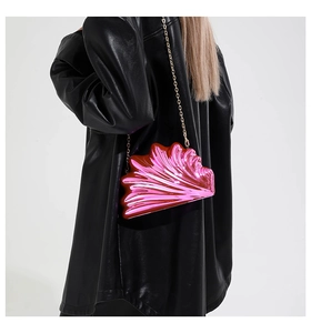 Detail view of metallic pink shell clutch bag with gold chain on model's shoulder