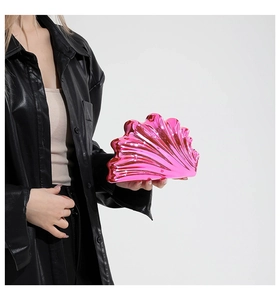 Close-up of metallic pink shell clutch bag with ribbed texture held by a model