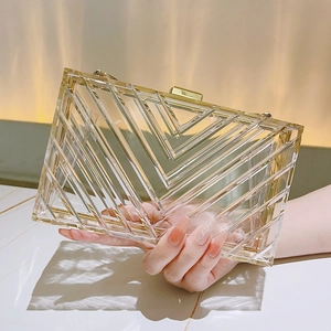 Macro shot of V-shaped geometric textures on a clear acrylic evening clutch with gold clasp