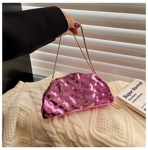Detail of glossy metallic pink acrylic clutch bag with thin gold chain and folded design