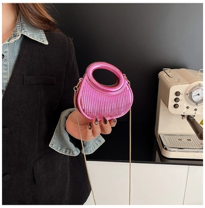 Detail of rose pink metallic clutch bag with pleated texture and gold chain strap