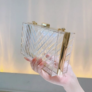 Close-up of transparent acrylic clutch bag featuring geometric V-shaped textures and gold clasp