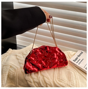 Close-up of a glossy red metallic clutch bag with golden chain strap on white knits