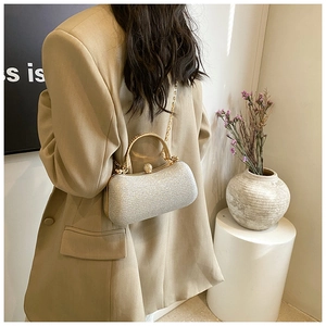 Silver glitter evening clutch with gold metal handle and chain strap worn on beige suit