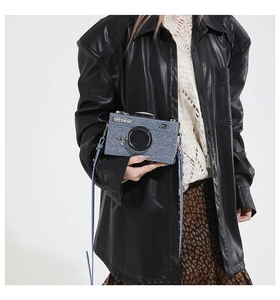 Detailaufnahme der hellblauen Kamera-Umhängetasche aus Denim an einem Model mit Lederjacke