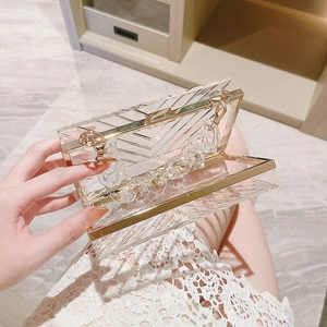 Macro detail of clear acrylic clutch bag showing geometric texture and gold metal frame
