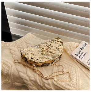 Detail of gold metallic crescent clutch with lava texture on a knitted background