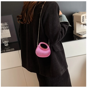 Pink acrylic evening bag with wave texture and gold chain strap worn by a model