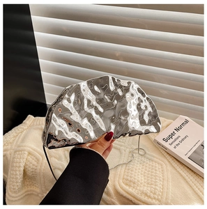 Detail of silver metallic seashell clutch bag with pleated texture and metal chain strap