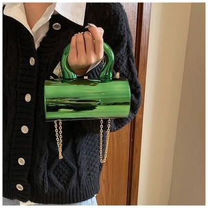 Detalle de bolso cilíndrico verde esmeralda metálico con cadena dorada y asa superior