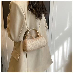 Close-up of golden glitter capsule clutch bag with metal handle and chain strap detail