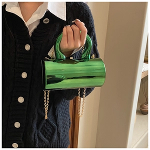 Detalle del bolso cilíndrico de acrílico espejo verde con cadena de metal oro