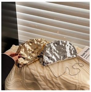 Close-up of gold and silver liquid metal textured clutch bags with stylish chain straps