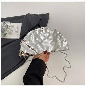 Detail of silver metallic clutch with hammered texture and fine chain strap