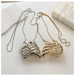 Detail von gold- und silberfarbenen Schnecken-Abendtaschen mit Spiegelglanz und Kugelketten